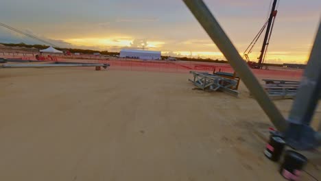 FPV-drone-shot-flying-through-a-construction-site,-during-a-sunny-evening