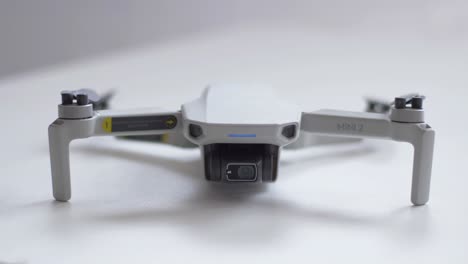 DJI-Mini-2-on-a-table-in-a-frontal-view,-with-the-front-LED-blinking-turned-on