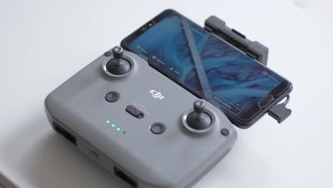 DJI-remote-control-connected-to-the-app-on-a-mobile-phone,-with-blinking-LEDs