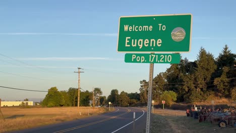 Señalización-En-La-Carretera-De-Eugene,-Oregon,-Dando-La-Bienvenida-Y-Enumerando-A-La-Población.