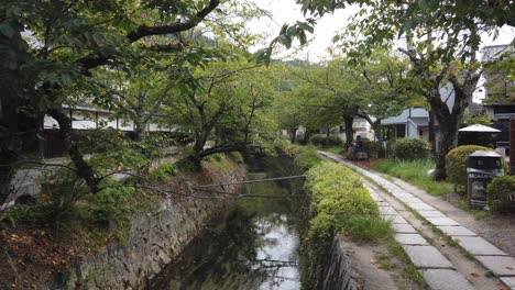 Toma-Manual-De-Turistas-Caminando-Por-El-Camino-Del-Filósofo,-Paisaje-Verde-Kyoto-Japón-En-Verano
