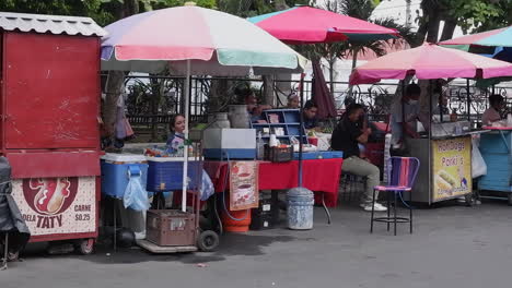Pan-across-street-food-carts-on-city-plaza-in-Santa-Ana,-El-Salvador