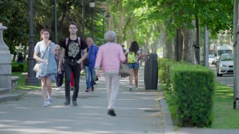 A-slow-motion-shot-of-mixed-people-strolling-through-a-park-in-Madrid,-Spain