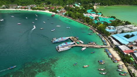 Koh-Phi-Phi-island-harbor-full-of-boats,-ferries-and-hotel-buildings,-aerial-shot-orbital