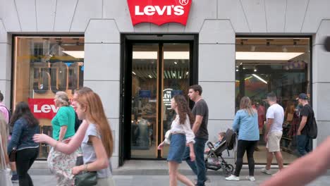 Shoppers-and-pedestrians-walk-past-the-American-multinational-clothing-company-brand,-Levi´s-store