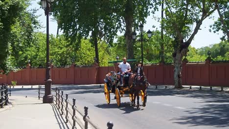 4k-Video-of-Tourists-ride-on-the-horse-and-carriages-while-visiting-The-Plaza-de-España-in-the-Parque-de-María-Luisa,-southern-Spain
