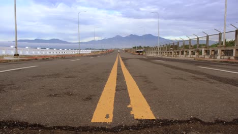 A-four-lane-road-with-only-cyclists-and-mountains-in-the-background