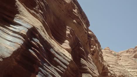 Pan-right-close-up-shot-of-a-large-textured-colorful-desert-sandstone-rock-wall-being-hit-by-the-sun-in-the-Buckskin-Gulch-slot-canyon-in-southern-Utah-near-Arizona-on-a-warm-sunny-spring-morning