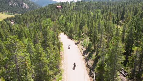 Two-motorcycle-riders-drive-towards-the-camera-with-an-aerial-view-dolly-backwards-in-the-mountains