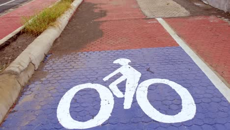 Ein-Fahrradmarkierungsschild-Auf-Dem-Weg-Mit-Nicht-Erkennbaren-Personen-Im-Hintergrund