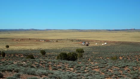 Extrem-Weite-Landschaftsaufnahme-Einer-Großen-Wüstenebene,-Die-Zur-Schafzucht-Genutzt-Wird,-Mit-Kleinen-Entfernten-Gebäuden-Und-Zelten-Und-Dem-Mit-Salbeibüschen-Bedeckten-Boden-In-Arizona-An-Einem-Warmen,-Sonnigen-Frühlingsmorgen