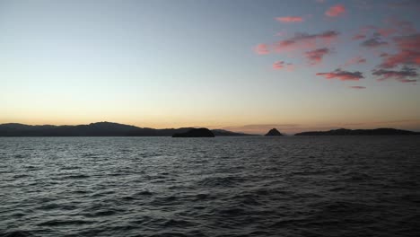 Moving-camera-view-of-mountains-and-small-islands-in-the-Gulf-of-Nicoya,-Costa-Rica,-during-sunset-with-pink-colored-clouds