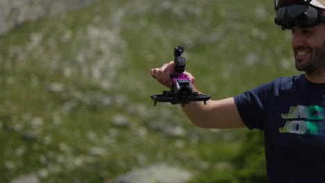 Smiling-drone-pilot-holding-Avata-quadcopter-with-Osmo-action-camera-mounted-on-top-with-mountain-landscape-in-background