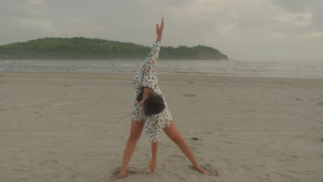 Eine-Frau-Führt-Anmutig-Yoga-Posen-Am-Ruhigen-Strand-Aus