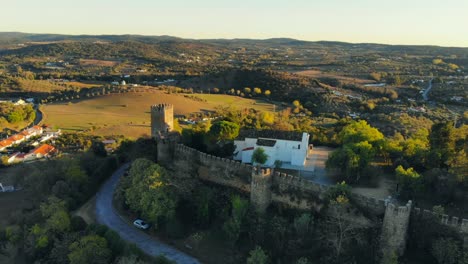Toma-De-Drone-De-Un-Edificio-De-Capilla-Blanca-En-Una-Colina-Con-Muralla-Medieval-Y-Torre-En-Alentejo,-Portugal