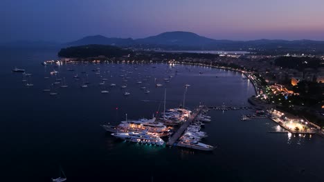 Atemberaubender-Nachtblick-Aus-Der-Luft-über-Die-Promenade-Der-Bucht-Von-Korfu-Mit-Vielen-Segelbooten-Und-Yachten