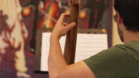 Musician-Playing-Double-Bass-Instrument-and-Looking-at-Music-Sheet,-Over-Shoulder-View-of-Arm-and-Fingers-on-Fingerboard