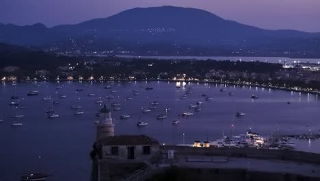 Night-aerial-close-up-view-over-Corfu-old-fortress-and-lighthouse-revealing-sailing-boats-behind-it