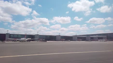 En-Un-Día-Parcialmente-Nublado,-La-Vista-Desde-La-Ventana-Del-Avión-Captura-El-Edificio-De-La-Terminal-Del-Aeropuerto-De-Estambul-Y-Los-Aviones-Estacionados-En-La-Plataforma.