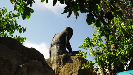 Estatua-De-Un-Hombre-Solitario-Sentado-Sobre-Una-Roca,-Esperando