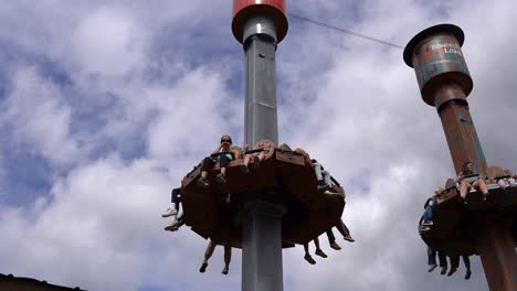 Children-and-adults-having-fun-in-free-fall-ride-at-Djurs-sommarland-amusement-park-in-Denmark---Long-angle-looking-up-at-ride-with-people