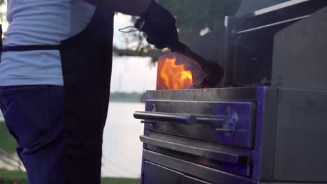 Mexican-latin-barbecue-griller-preparing-charcoal-on-grid-fire-for-steak-raw-meat-at-sunset-garden-lake-party-flames