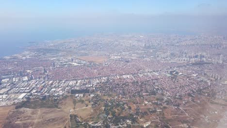 In-the-daytime,-a-view-of-Istanbul-city-through-the-airplane-window,-showcasing-a-dense-cityscape-and-the-coastal-shoreline