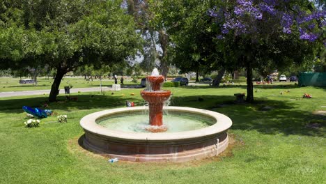 Low-panning-aerial-shot-of-a-decorative-fountain-surrounded-by-flowered-grave-sites-at-a-mortuary-in-California