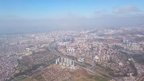 cinematic-daytime-view-of-Istanbul-city-through-the-airplane-window,-featuring-a-bustling-cityscape-with-the-E80-highway-running-amidst-crowded-buildings-in-Esenyurt