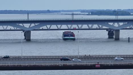 Drohnenansicht-Eines-Containerschiffs,-Das-Unter-Der-Alfa-Menta-Moerdijk-Brücke-Mit-Vorbeifahrenden-Autos-In-Den-Niederlanden-Fährt