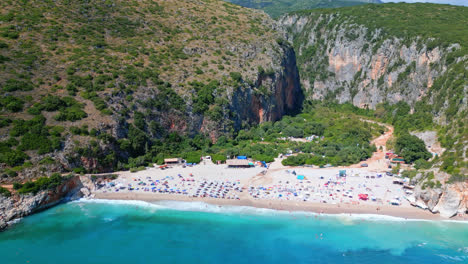 Aerial-drone-forward-moving-shot-flying-high-over-secluded-Gjipe-beach,-Albania-on-a-sunny-day