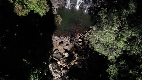 Reveal-of-a-secluded-natural-swimming-hole-and-waterfall-hidden-deep-amongst-the-dense-rainforest-trees