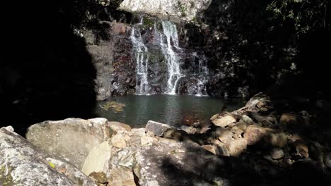 Sunshine-lights-up-a-secluded-rainforest-waterfall-and-natural-swimming-hole