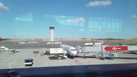 In-partly-cloudy-daylight,-ground-services-load-a-parked-Turkish-Airlines-aircraft-on-the-apron-of-Istanbul-Airport