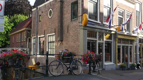 Man-Riding-Bicycle-Passing-In-Front-Of-'t-Kaaswinkeltje-Cheese-Shop-At-Lange-Tiendeweg-Street-In-Gouda,-Netherlands