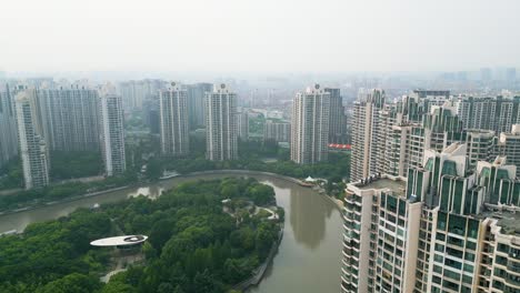Die-Nach-Oben-Geneigte-Aeria-Enthüllt-Einen-Grünen-Freizeitpark-Und-Einen-Geschwungenen-Kanal-Inmitten-Von-Wohngebäuden-Im-Bezirk-Pu-Tuo-Qu-In-Shanghai,-China