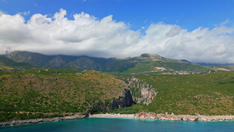Pan-shot-from-left-to-right-over-Gjipe-Beach-in-Albania-with-white-clouds-passing-in-the-background-on-a-bright-sunny-day