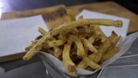 Slow-revealing-shot-of-a-portion-of-fries-served-in-a-metal-basket