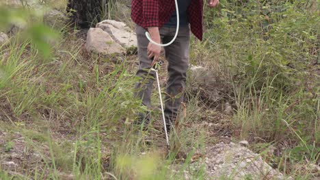 Man-in-the-forest-watering-new-trees,-pesticide-or-fertilizer,-using-a-backpack-sprayer