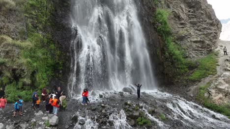 Drone-rotating-and-circling-around-waterfalls-with-people-enjoying-and-relaxing-in-Pakistan,-Mantoka,-Skardu