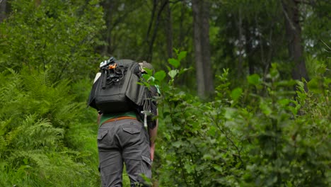 Male-content-creator-hikes-along-climbing-forest-path,-rear-view