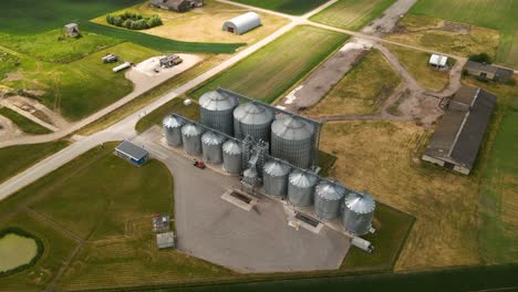 Vista-Por-Drones-De-La-Torre-De-Silos-Agrícolas-De-Almacenamiento-De-Productos-Agrícolas-Y-Elevadores-De-Granos-En-Medio-De-Un-Campo-Cultivado-Verde