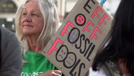 In-Zeitlupe-Hält-Eine-Frau-Ein-Plakat-Mit-Der-Aufschrift-„Scheiß-Weg-Von-Fossilen-Brennstoffen“-Auf-Einer-Rebellion-Gegen-Den-Klimawandel,-Die-Gegen-Die-Abhängigkeit-Von-Fossilen-Brennstoffen-Protestiert