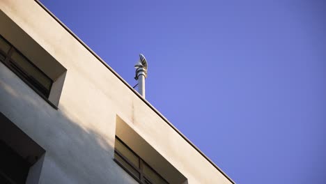 Low-angle-view-of-a-spinning-small-wind-turbine-on-a-building's-roof