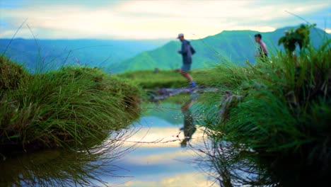 trail-runners-running-to-the-mountains-with-a-beautiful-push-in-low-angle-puddle-shot
