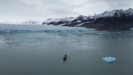 Expedition-boat-sailing-towards-a-glacier-with-mountain-in-its-backdrop