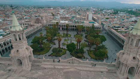 Cloudy-day-drone-pan-from-left-to-right,-capturing-the-rear-view-of-the-Arequipa-Cathedral,-its-twin-towers,-and-the-Plaza-de-Armas,-ending-with-a-frontal-view