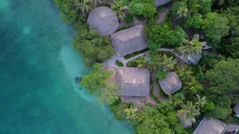 Exotic-thatched-roof-bungalows-on-turquoise-crystal-water-in-Caribbean-island