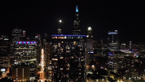 Aerial-view-approaching-a-deluxe-condo-with-full-moon,-Chicago-skyline-background