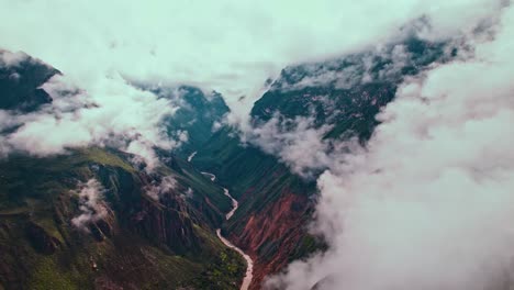 Aerial-drone-flight-backward-reveals-Colca-Canyon's-vastness,-post-rain-clouds,-lush-greenery,-and-Colca-River